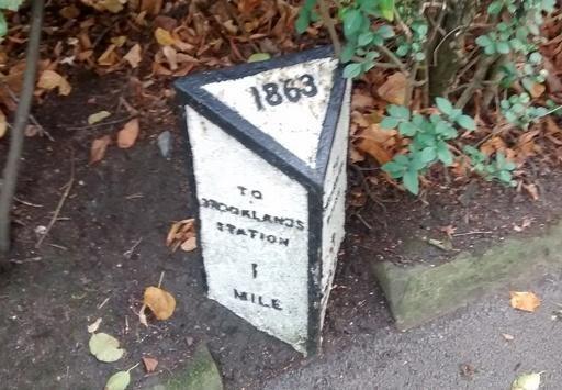 Milestone on Brooklands Road side showing distance as 1 mile to Brooklands Station.